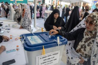 a woman putting a slip of paper into a ballot box