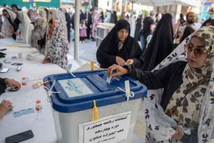 a woman putting a slip of paper into a ballot box